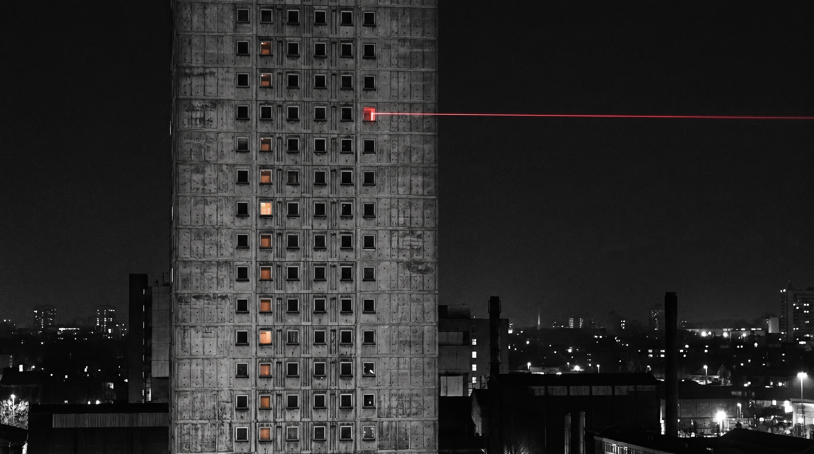 Brutalist concrete tower at night with grid of windows and a red laser beam projecting outward into the dark city
